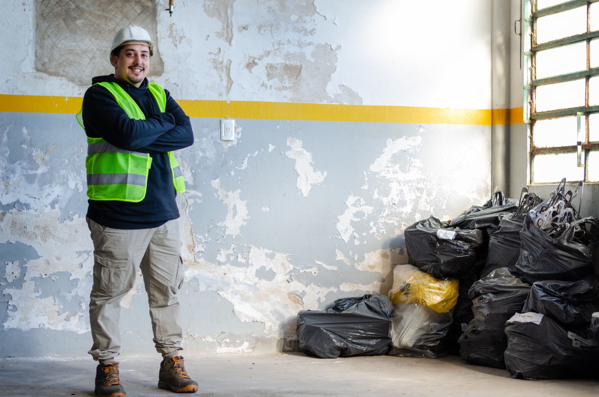 Portrait of male environmentalist with arms crossed wearing safety gear cleans up trash at warehouse. Recycle concept